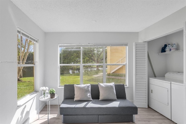 interior space with a textured ceiling, washer and dryer, a healthy amount of sunlight, and light wood-type flooring