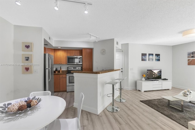 kitchen featuring stainless steel appliances, a breakfast bar, a textured ceiling, and light wood-type flooring