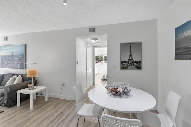 dining space with a textured ceiling and light wood-type flooring