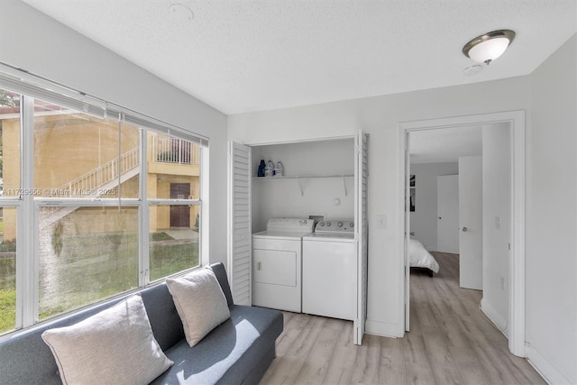 laundry area with light hardwood / wood-style flooring, washing machine and dryer, and a textured ceiling