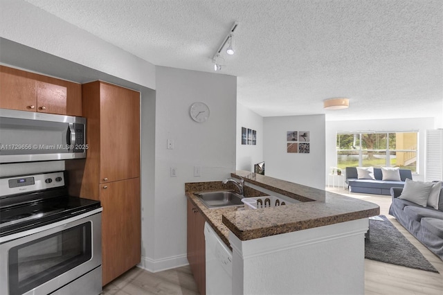 kitchen featuring track lighting, appliances with stainless steel finishes, sink, and a textured ceiling