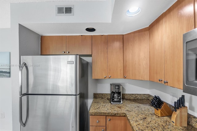 kitchen with stainless steel refrigerator and light stone countertops