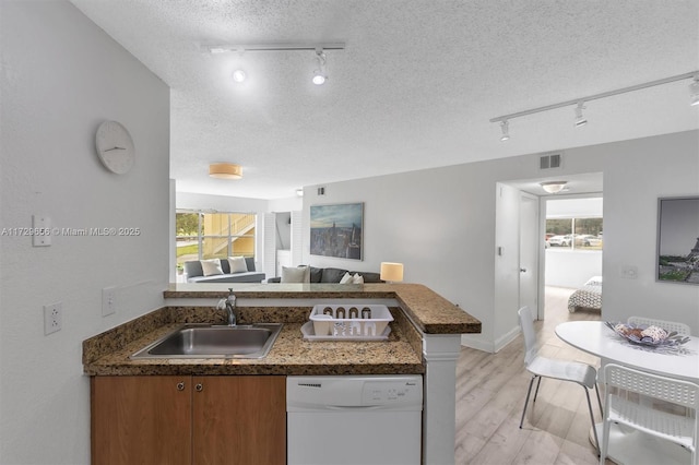 kitchen featuring dishwasher, sink, kitchen peninsula, a textured ceiling, and light hardwood / wood-style flooring