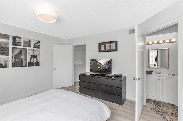 bedroom with ensuite bath, a textured ceiling, a closet, and a walk in closet