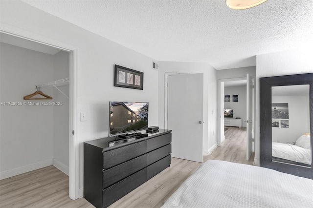 bedroom featuring a closet, light hardwood / wood-style flooring, and a textured ceiling