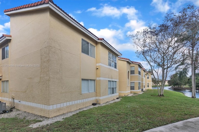 view of side of property featuring a water view and a lawn