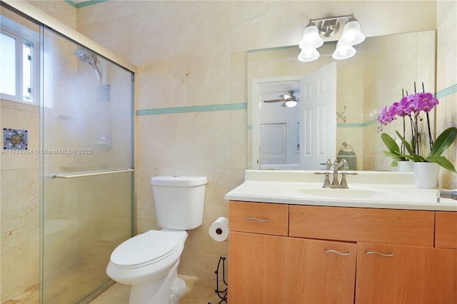 bathroom with a shower with door, vanity, tile walls, and toilet