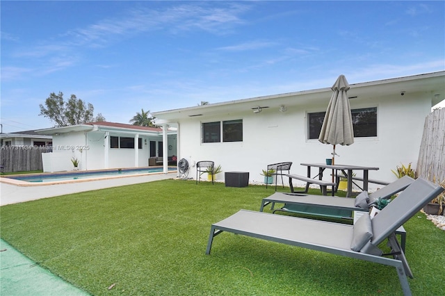 back of property with a fenced in pool and a lawn