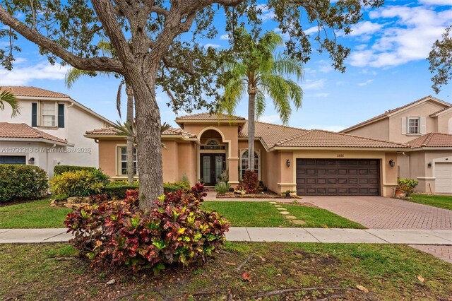 mediterranean / spanish house featuring a garage and a front lawn