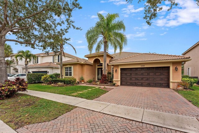 mediterranean / spanish-style home featuring a garage and a front lawn