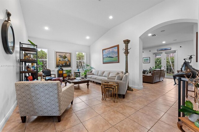 tiled living room featuring vaulted ceiling, plenty of natural light, and french doors