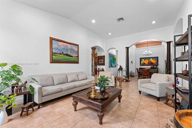 living room featuring an inviting chandelier, light tile patterned floors, vaulted ceiling, and ornate columns