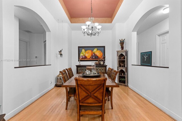 dining area with a tray ceiling and wood-type flooring