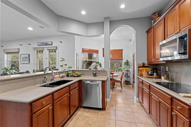 kitchen with sink, backsplash, light tile patterned floors, kitchen peninsula, and stainless steel appliances