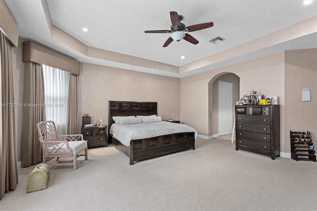 bedroom featuring ceiling fan, a raised ceiling, and light colored carpet