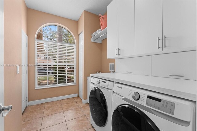 laundry area with cabinets, light tile patterned floors, and washing machine and clothes dryer