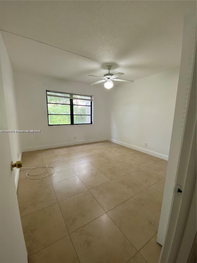 tiled spare room featuring ceiling fan