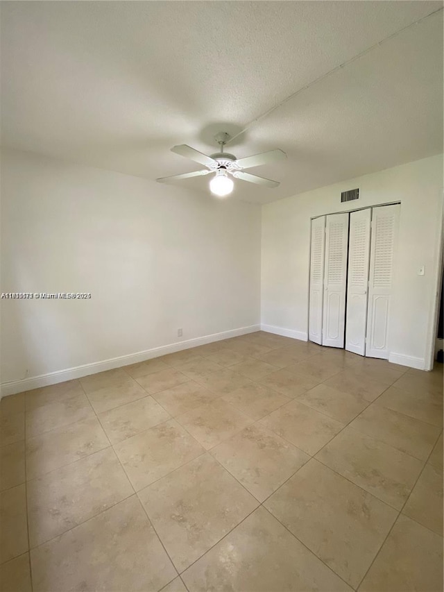 unfurnished bedroom with light tile patterned floors, a textured ceiling, ceiling fan, and a closet