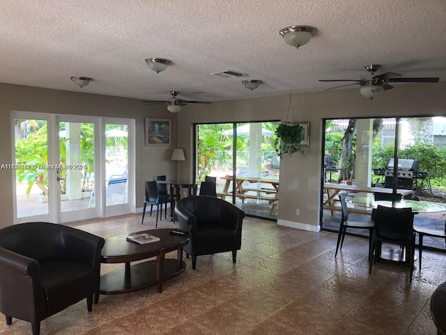 living room with ceiling fan, a textured ceiling, and a healthy amount of sunlight