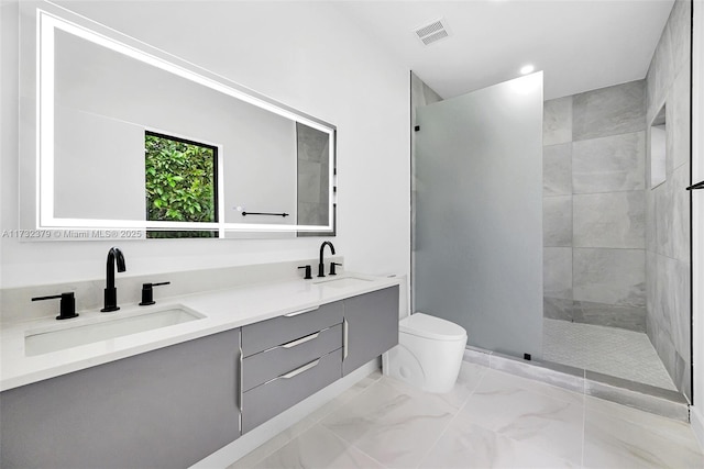 bathroom featuring vanity, toilet, and a tile shower