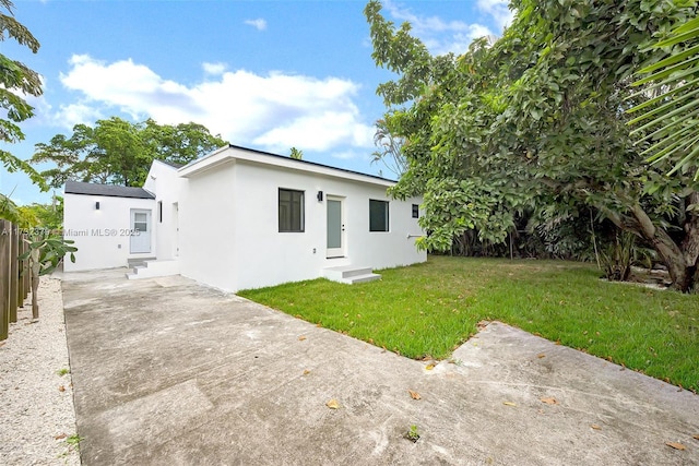 back of property featuring a patio area and a lawn