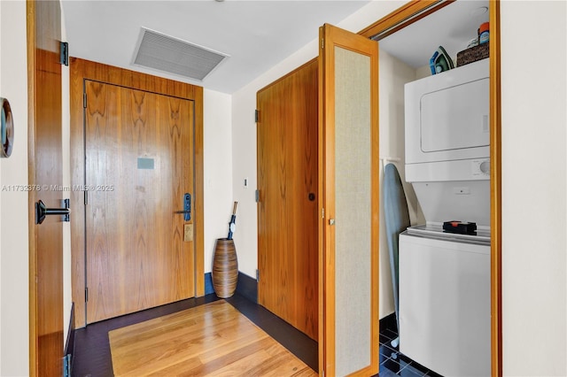 laundry area with stacked washer / dryer and hardwood / wood-style flooring