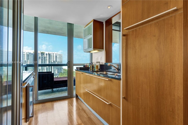 kitchen featuring expansive windows, sink, and light hardwood / wood-style flooring