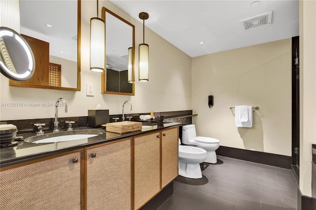 bathroom with tile patterned flooring, a bidet, vanity, and toilet