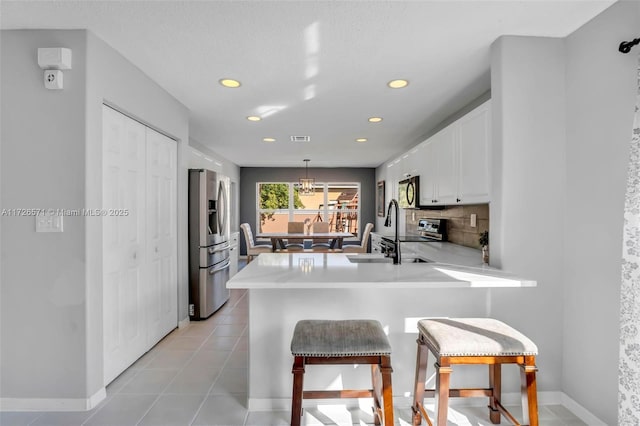 kitchen featuring sink, appliances with stainless steel finishes, white cabinetry, decorative light fixtures, and kitchen peninsula