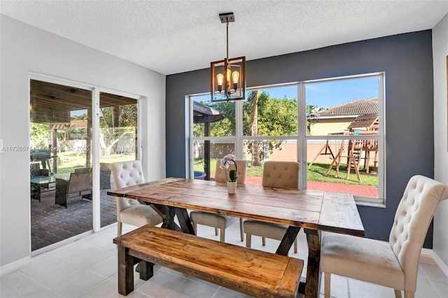 dining space featuring light tile patterned flooring, a healthy amount of sunlight, a chandelier, and a textured ceiling