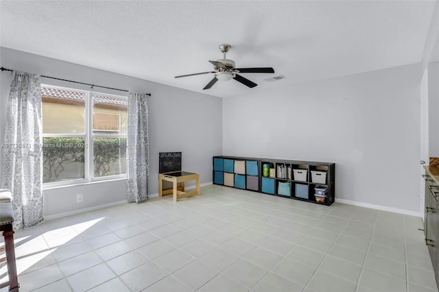 living area with ceiling fan, a textured ceiling, and light tile patterned floors