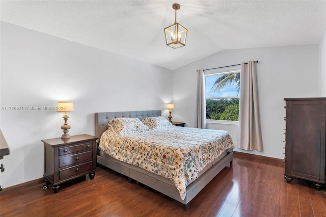 bedroom featuring lofted ceiling, dark wood-type flooring, a textured ceiling, and an inviting chandelier