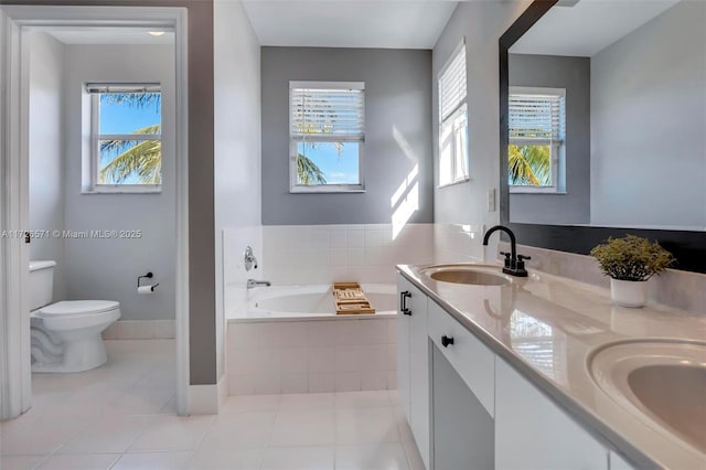 bathroom featuring vanity, a wealth of natural light, tile patterned flooring, and tiled tub