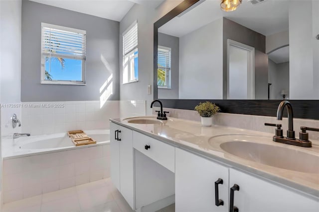 bathroom with vanity, tile patterned flooring, and tiled tub