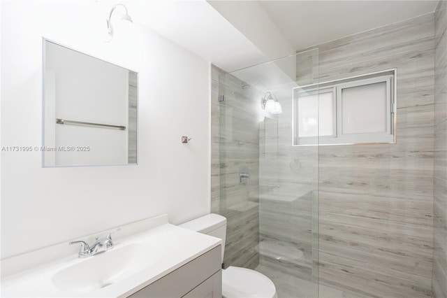 bathroom featuring vanity, a shower with shower door, and toilet