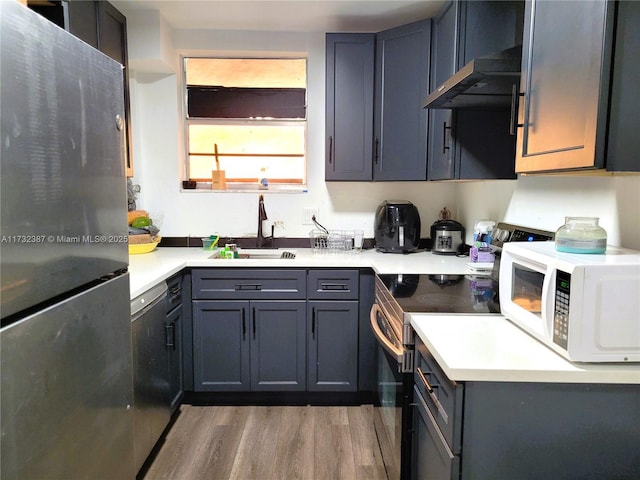 kitchen featuring appliances with stainless steel finishes, gray cabinets, a sink, and wood finished floors