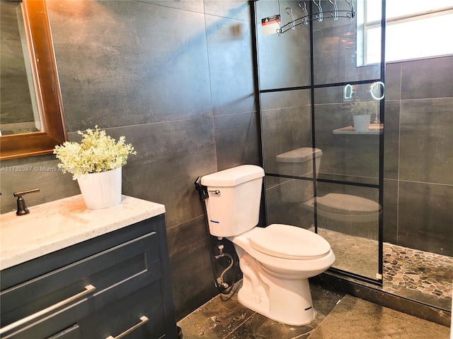 full bathroom featuring a tile shower, tile walls, toilet, and vanity