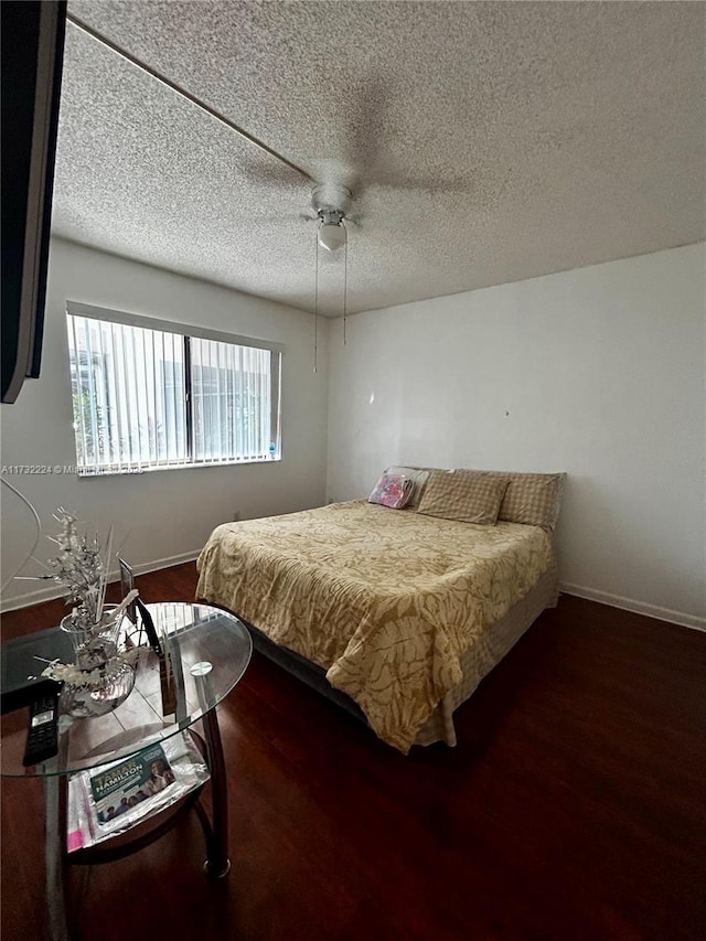 bedroom featuring dark wood-type flooring, a textured ceiling, and ceiling fan