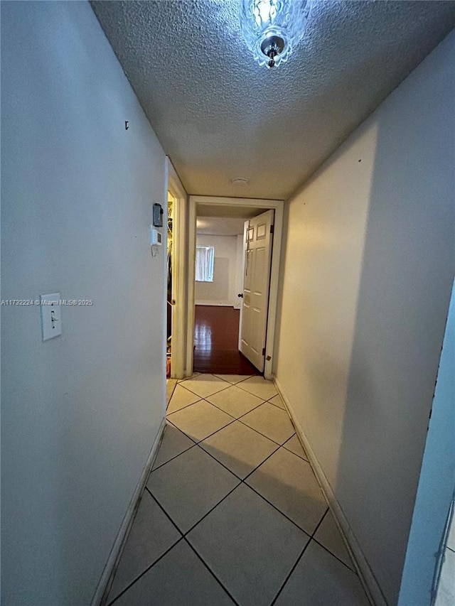 hallway with light tile patterned floors and a textured ceiling