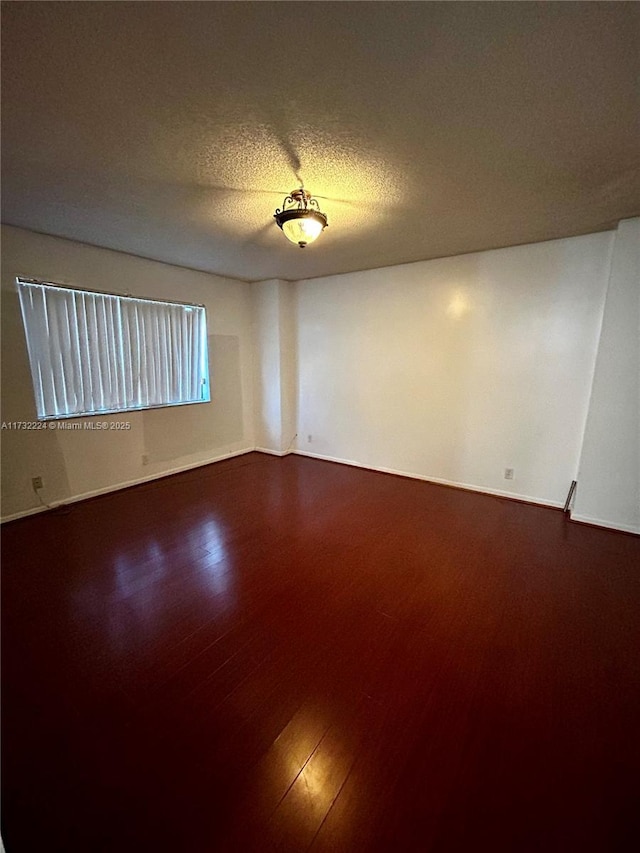 unfurnished room with hardwood / wood-style flooring and a textured ceiling