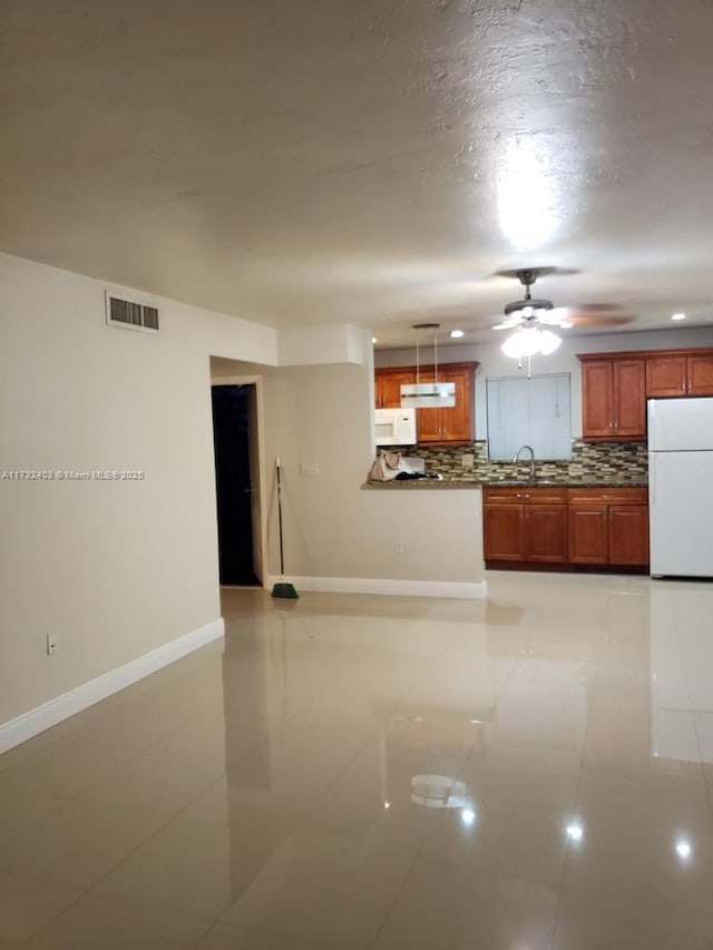 kitchen featuring sink, decorative backsplash, hanging light fixtures, kitchen peninsula, and white appliances