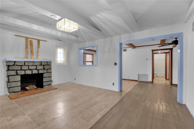 unfurnished living room featuring a fireplace, beamed ceiling, and a textured ceiling