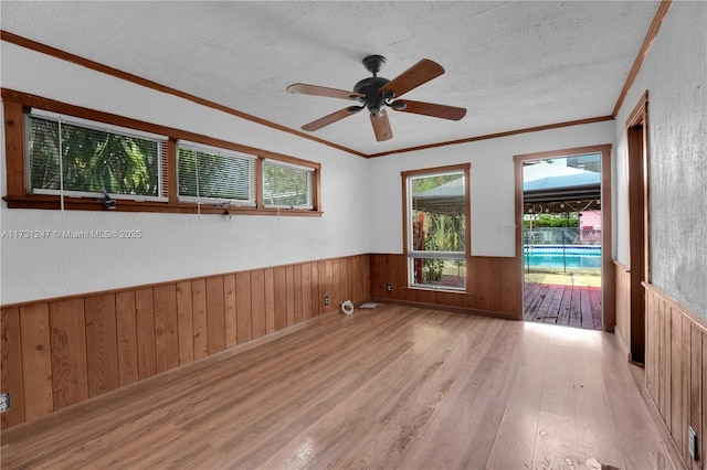 unfurnished room with ceiling fan, ornamental molding, light hardwood / wood-style floors, and a textured ceiling