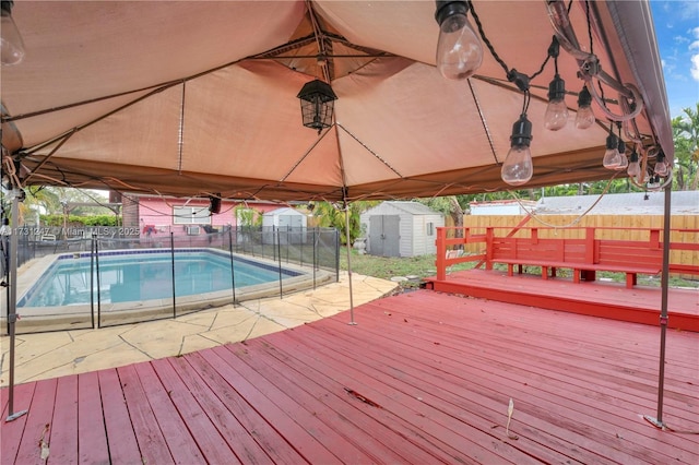 wooden terrace with a fenced in pool and a storage shed