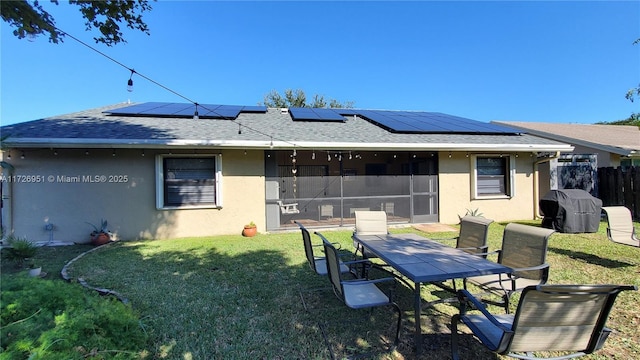 back of property featuring a yard, a sunroom, and solar panels