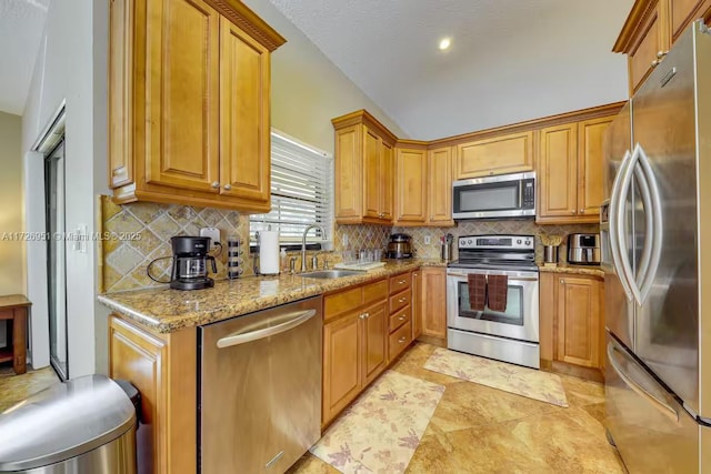 kitchen with sink, light tile patterned floors, stainless steel appliances, light stone counters, and decorative backsplash