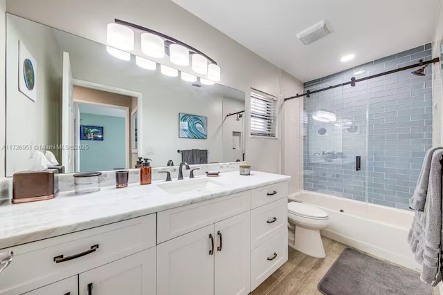 full bathroom with tiled shower / bath, wood-type flooring, toilet, and vanity