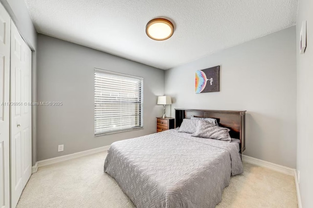 bedroom with light colored carpet, a closet, and a textured ceiling