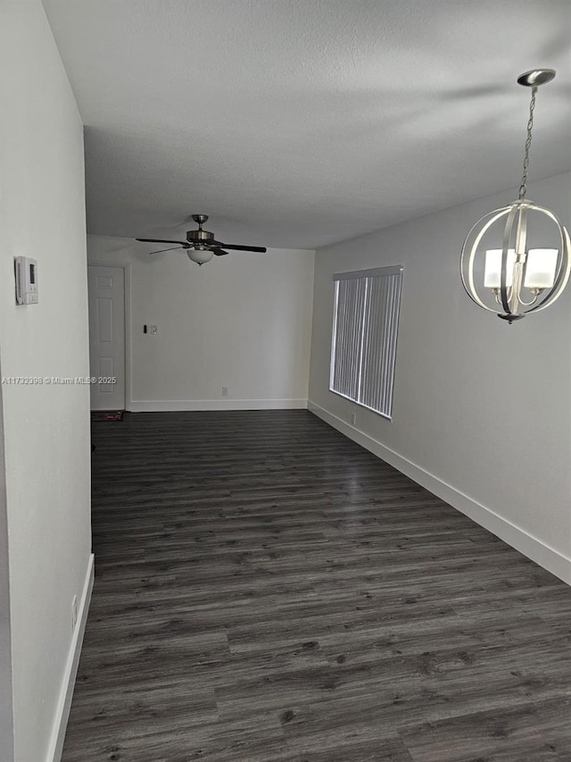 spare room featuring dark hardwood / wood-style floors and ceiling fan with notable chandelier