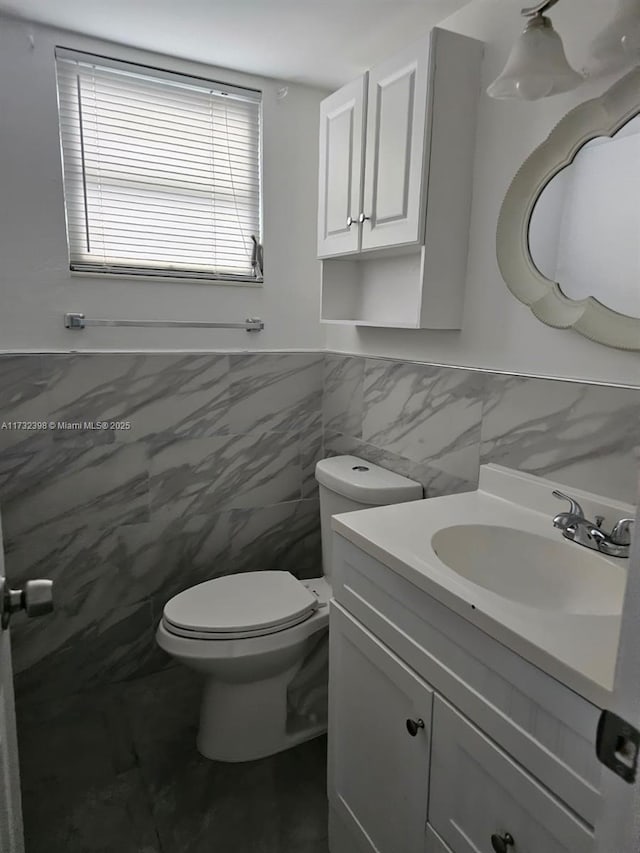 bathroom featuring vanity, toilet, and tile walls